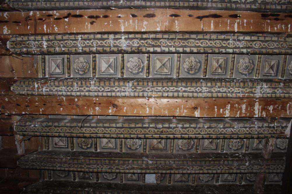 Dettaglio del soffitto a cassettoni dipinto: travi a treccia e pannelli con fiori